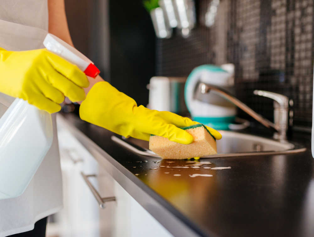 Femme nettoyant les armoires de cuisine avec éponge et nettoyant par pulvérisation