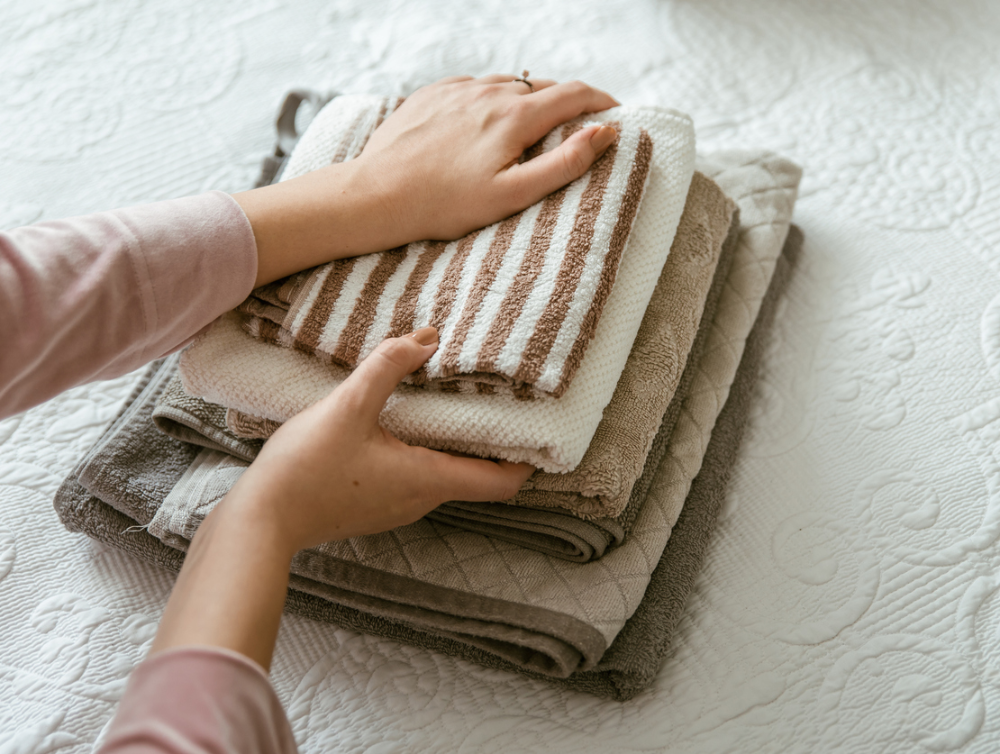 Vêtements pliants de femme dans la chambre à coucher, organisant la lessive dans des boîtes et des paniers