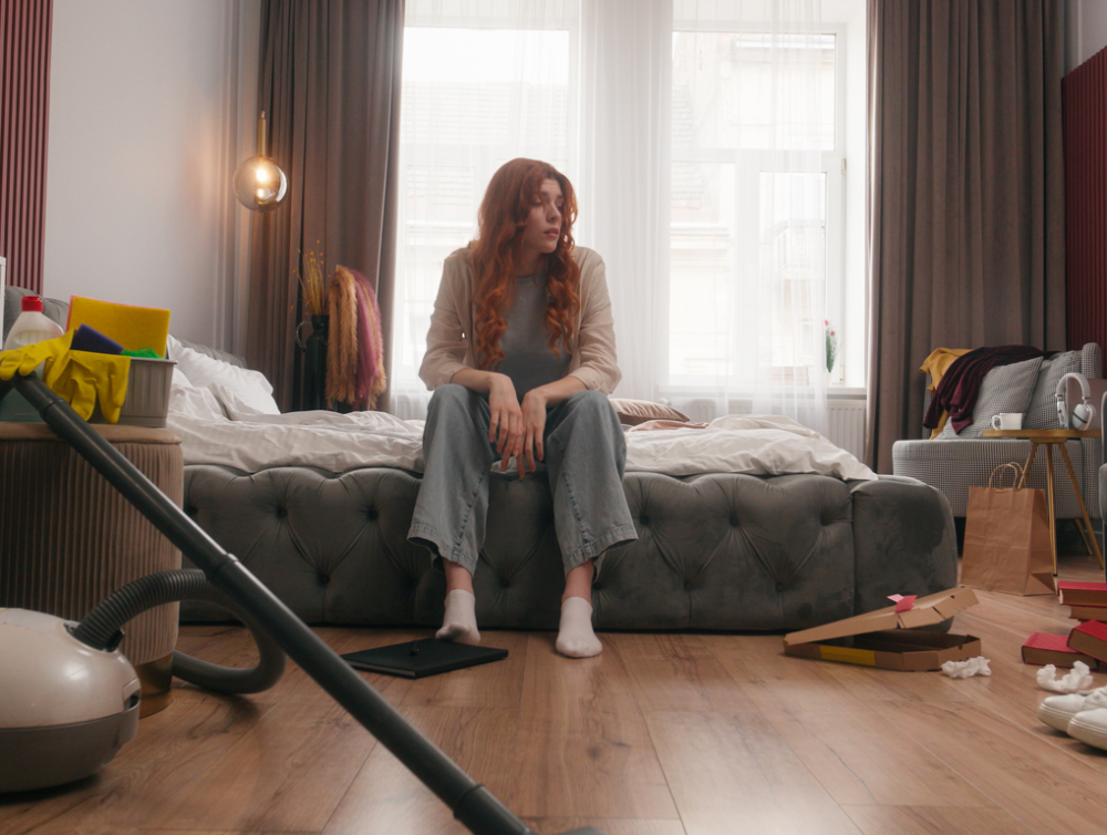 Exhausted sad upset Caucasian woman girl female homeowner lady housewife tired headache stress anxious frustrated mess in bedroom cleaning home chore problem trouble messy dirty housekeeping cleanup