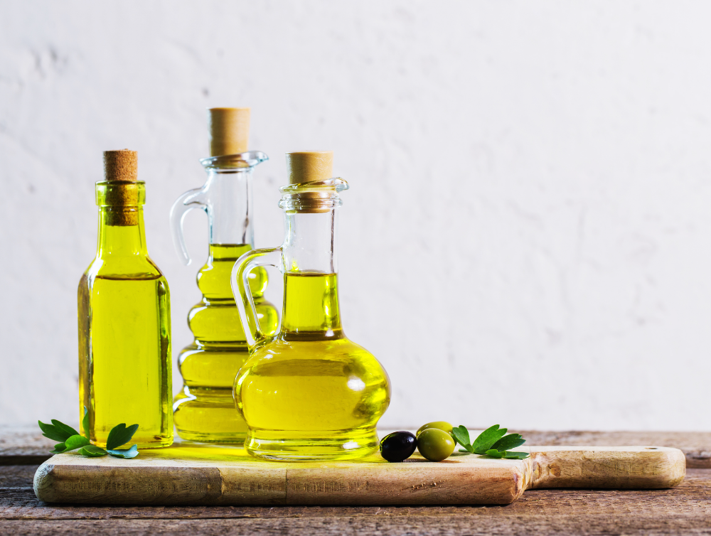 bouteilles d’huile d’olive extra vierge et des olives noires et vertes sur une planche à découper pour le ménage à Nice